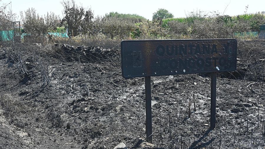 Vista del cartel que anuncia la entrada a Quintana y Congosto, en León, calcinado por el incendio.