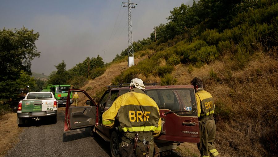 Escena de extinción de incendio forestal: bomberos con uniformes amarillos y un todoterreno rojo con las siglas BRIF en una zona montañosa.