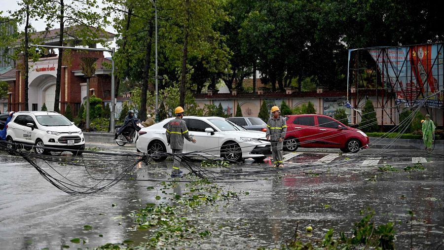 Trabajadores recogen cables de comunicación caídos sobre una carretera tras el paso del tifón Kajiki por Vietnam