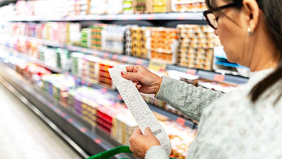Una mujer comprando en el supermercado y y revisando su recibo