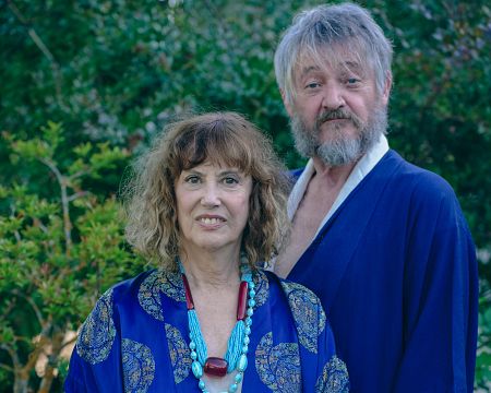 Dos personas, una mujer con kimono azul estampado y una sonrisa, y un hombre con kimono azul liso y expresión seria, en un jardín. Posible anuncio de productos sin gluten.