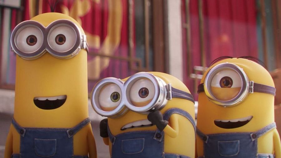 Kevin, Bob y Stuart, los Minions, aparecen en una imagen con fondo rojo.  Kevin sonríe, Bob se ajusta las gafas y Stuart también sonríe.