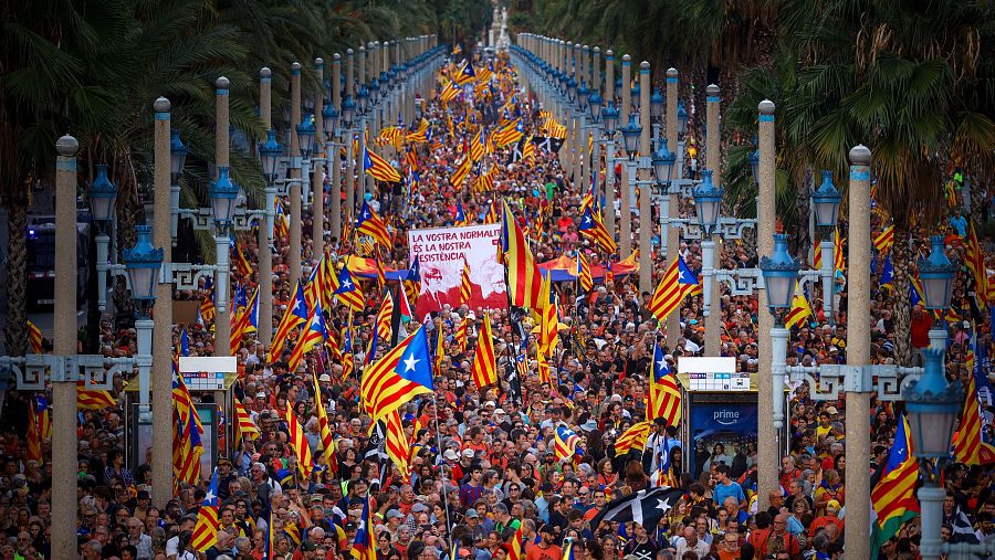 Manifestación multitudinaria en Barcelona con numerosas banderas independentistas catalanas y una pancarta que dice: 
