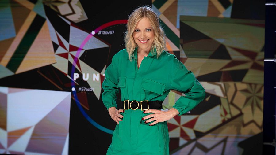 Tània Sarrias, vestida amb un mono verd i cinturó negre, al plató de 'Punts de vista'. Es veu part del nom del programa i alguns hashtags.