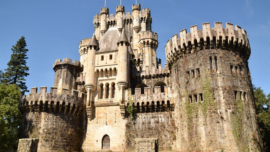 Vista frontal del Castillo de Butrón en Gatika, con sus torres y murallas de estilo neogótico rodeadas de vegetación.