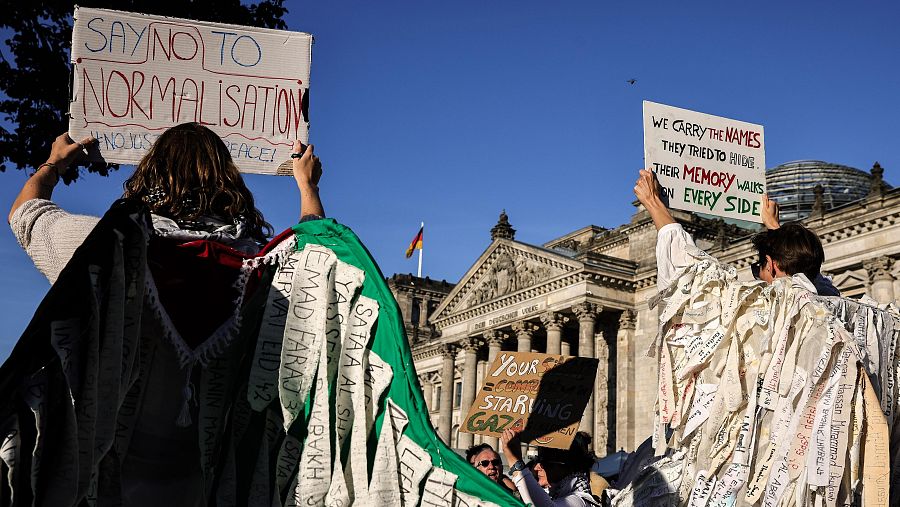 Imagen de dos manifestantes portando pancartas en Berlín