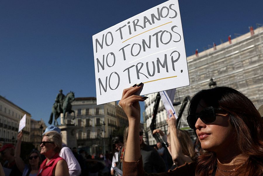 Una manifestante sostiene un cartel en protesta contra el presidente estadounidense Donald Trump en la Puerta del Sol de Madrid