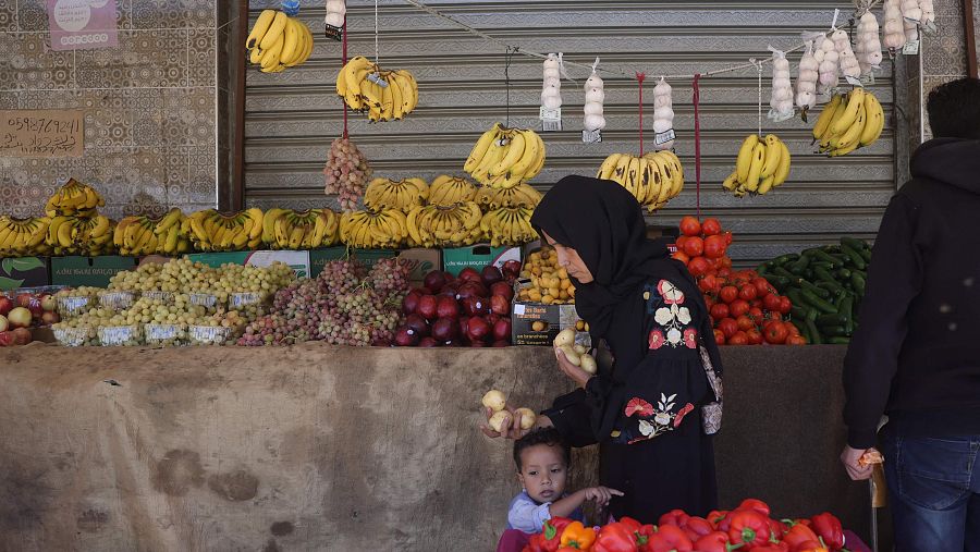 Una mujer acompañada de un niño compra frutas y verduras frescas en un mercado de Deir el-Balah, en el centro de la Franja de Gaza, el 18 de octubre de 2025.
