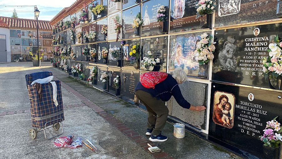 Una mujer limpia una lápida en el cementerio de Guadix