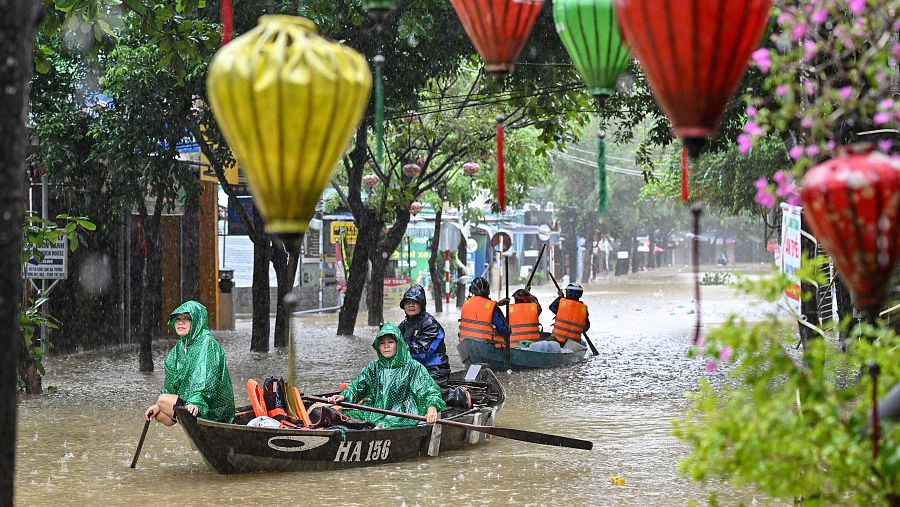 Varias personas navegan con barcas las calles inundadas de Hoi An.