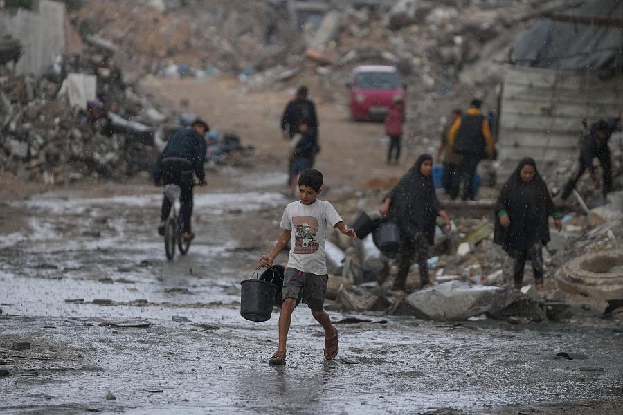 Un niño lleva dos cubos vacíos de camino a recoger agua en medio de una tormenta en el barrio de Sheikh Radwan, en Ciudad de Gaza