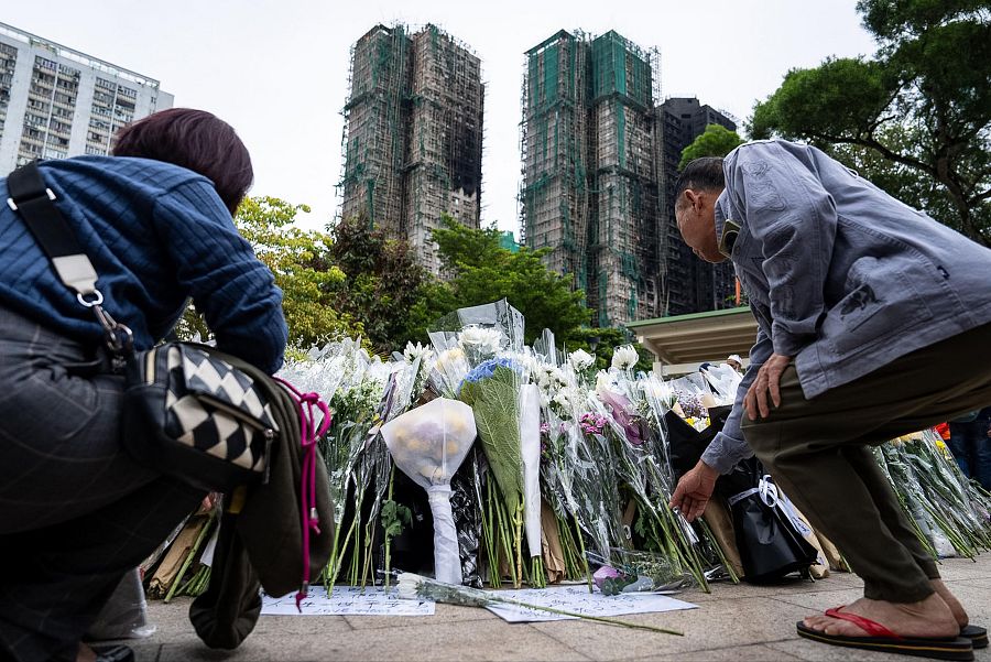 La gente ofrece flores a las víctimas cerca del lugar del mortal incendio en Wang Fuk Court, Hong Kong