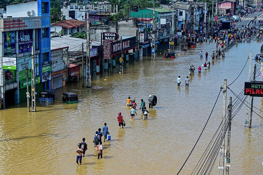 La gente camina por una calle inundada tras las fuertes lluvias caídas en Wellampitiya, en las afueras de Colombo, Sri Lanka