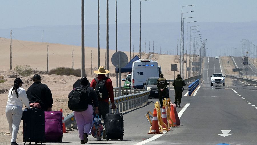 Migrantes caminan de regreso a Chile tras ser denegados su ingreso a Perú, cerca del paso fronterizo de Cachalluta
