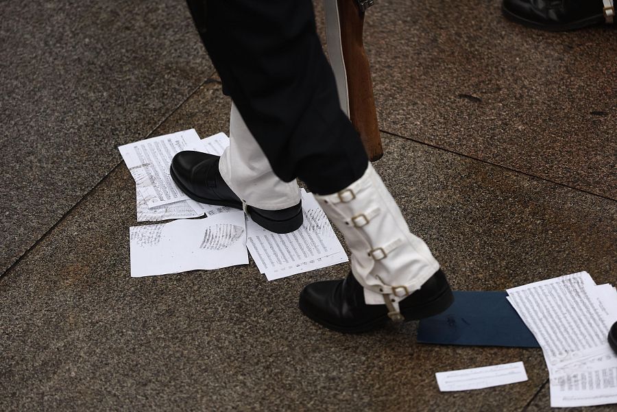 Un miembro de la Unidad Militar pisa algunas partituras caídas en el suelo