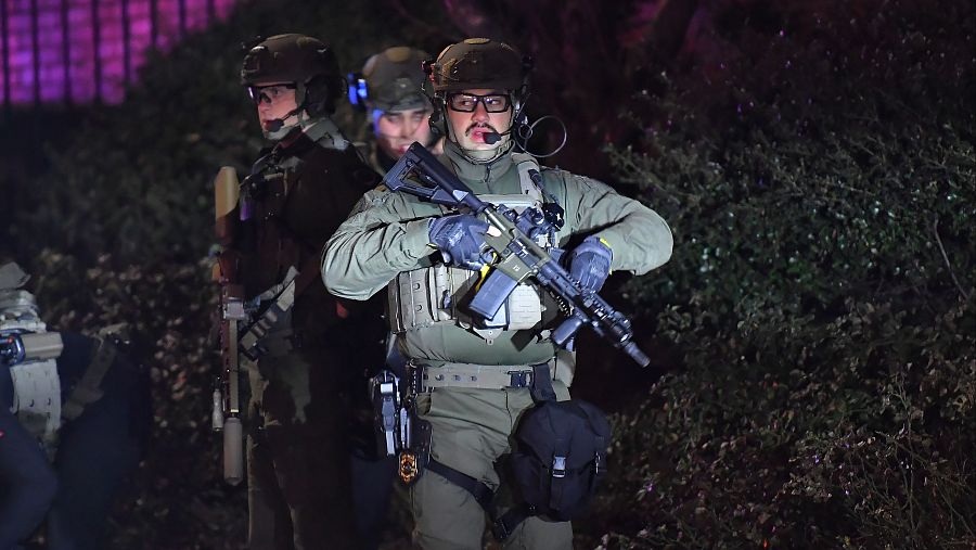 Agentes de las fuerzas de seguridad portan rifles en una calle de un barrio cercano a la Universidad Brown