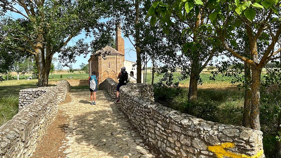 Peregrinos cruzan el puente de piedra hacia la ermita de la Virgen del Puente, a las afueras de Sahagún, uno de los puntos emblemáticos del Camino Francés a su paso por León