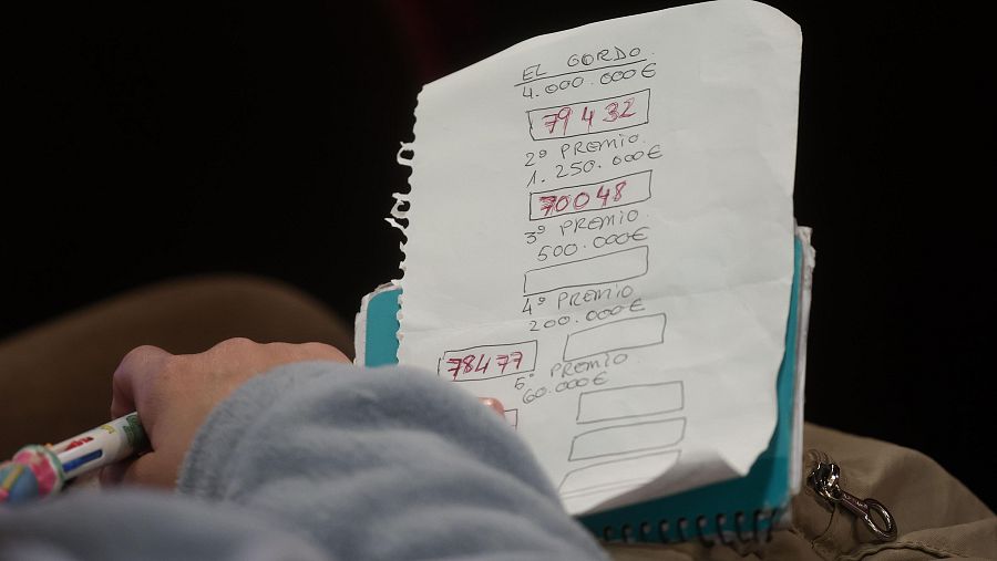 Un hombre apunta los números premiados que van saliendo en el sorteo de la Lotería de Navidad