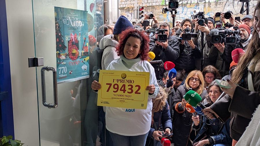 La lotera de la administración de lotería de La Elipa (Madrid) donde ha caído el primer premio exhibe el número ante la prensa