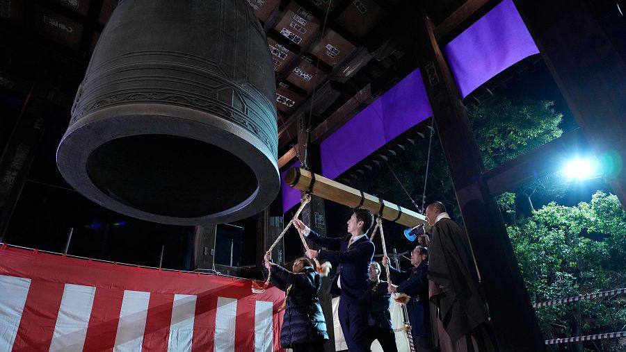 Varias personas golpean una campana gigante para celebrar el Año Nuevo en el templo budista Zojoji.