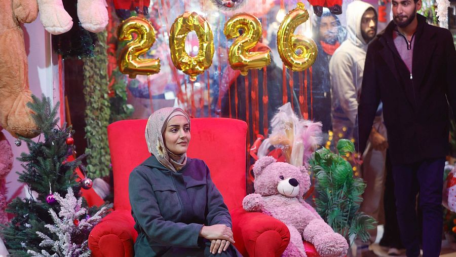 Una mujer palestina sentada entre adornos de Año Nuevo en la ciudad de Gaza.