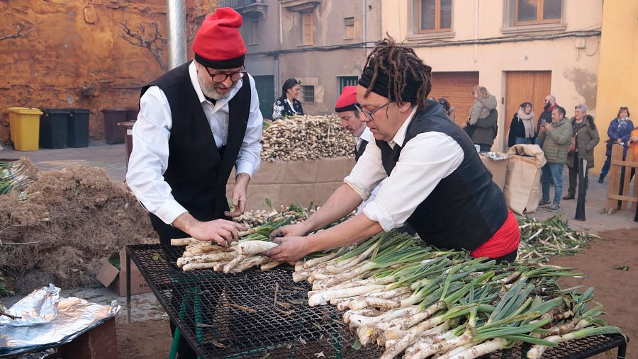 Un grup d'homes prepara un manat de calçots per ser cuits a Valls