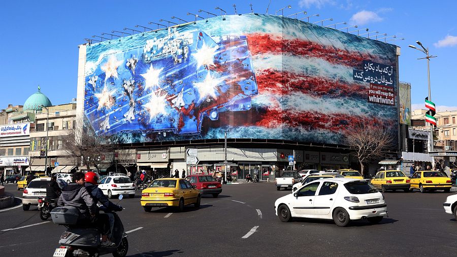 Iraníes circulan cerca de un enorme cartel anti-EE.UU. colgado en la plaza de la Revolución en Teherán