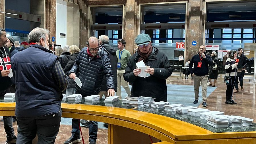 Ciudadanos observan las papeletas para ejercer su derecho al voto en el Ayuntamiento de Zaragoza.