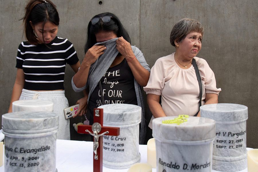 Familiar de una de las víctimas de las ejecuciones extrajudiciales de la guerra contra las drogas llora junto a las urnas de las víctimas durante los ritos de inhumación