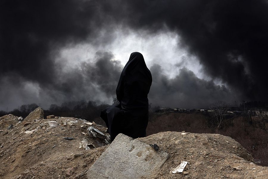 Una mujer observa la nube tóxica que cubre el cielo de Teherán tras los ataques israelíes contra instalaciones petroleras