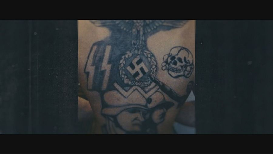 En la espalda de una persona se observan tatuajes con símbolos nazis: un águila imperial, una esvástica con corona de laurel, las letras SS, una calavera y la imagen de un soldado con casco.