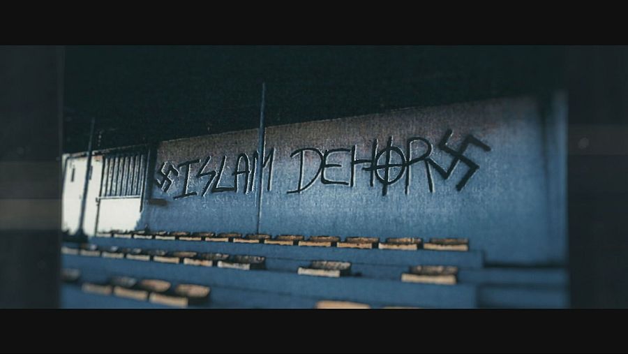 Una pintada en una pared azul grisáceo exhibe la frase en francés 