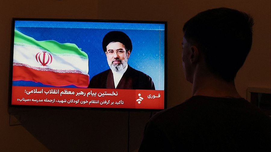 Un hombre observa una declaración televisada del nuevo líder supremo de Irán, Mojtaba Jamenei.