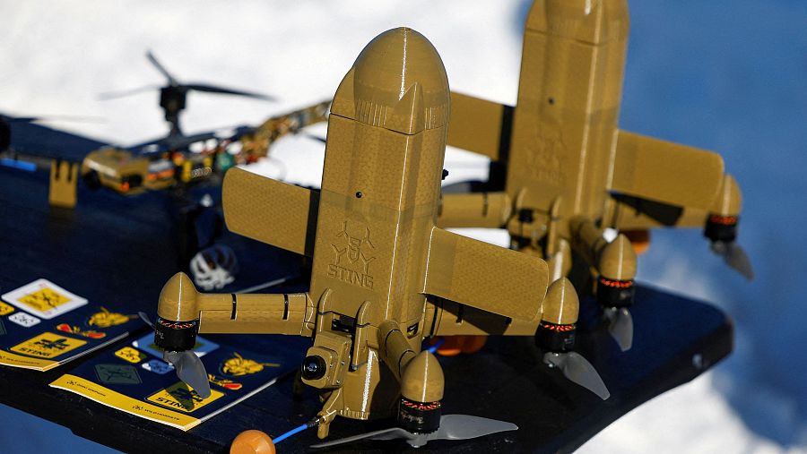 La fotografía muestra varios drones de color marrón claro sobre una mesa oscura, incluyendo dos con forma de misil y la inscripción 