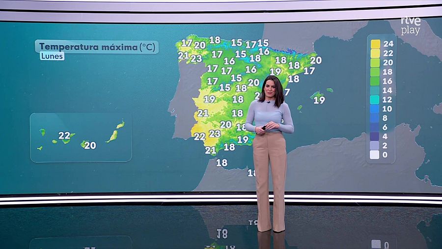 Una mujer de pelo oscuro, vestida con un jersey azul claro, presenta el pronóstico del tiempo frente a un mapa de España. El mapa muestra las temperaturas máximas previstas para el lunes, con diferentes colores que indican los rangos de temperatura.