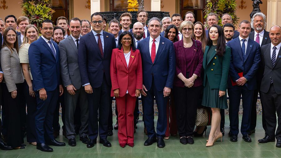 Delcy Rodríguez y Doug Burgum, junto a sus delegaciones, posan para una fotografía. La imagen muestra a ambos individuos en un evento oficial, con Rodríguez vistiendo de rojo y Burgum de azul, en una fecha específica.
