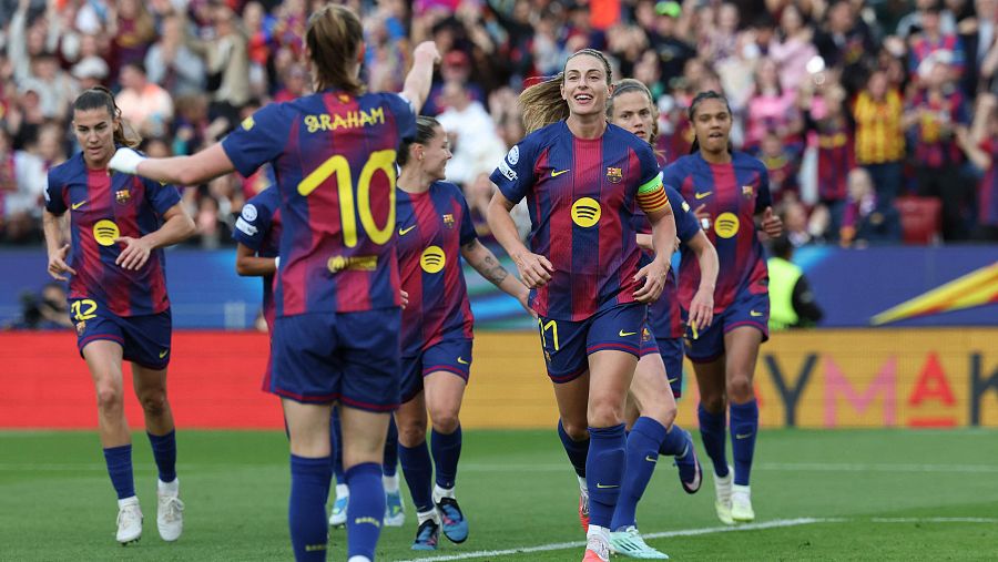 Dos jugadoras del FC Barcelona, identificadas por sus dorsales 11 y 10, celebran un gol en un estadio. Se observa a Alexia Putellas, con brazalete de capitana, y a Caroline Graham Hansen, ambas vestidas con la equipación azulgrana.