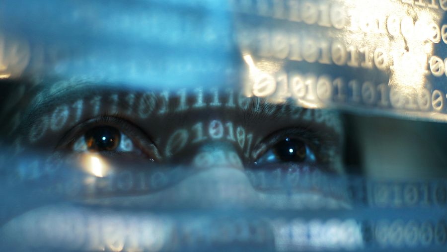 Detalle de la mirada de una persona. En su rostro se refleja una cadena interminable de unos y ceros