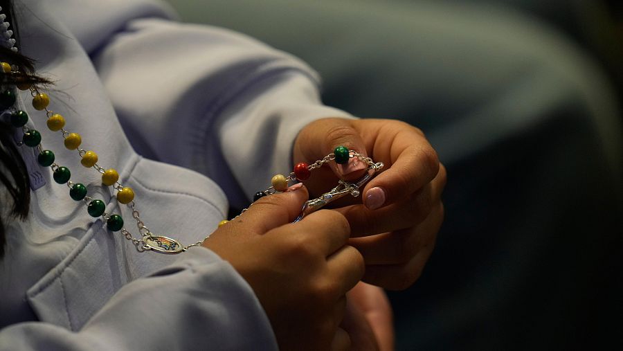 Una mujer sostiene un rosario