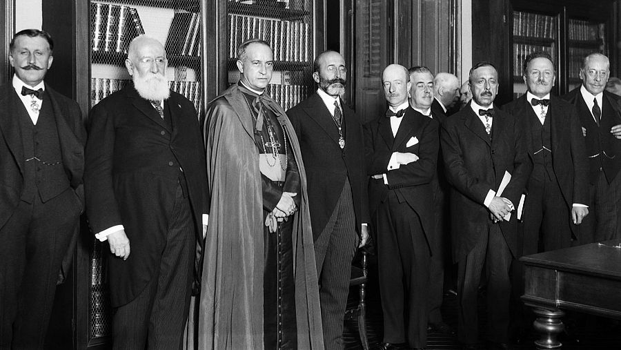 Celebración de la primera Fiesta del Libro en España el 15 de octubre de 1926. Siete hombres, incluyendo a Joaquín Álvarez Quintero, Francisco Rodríguez Marín, el Obispo Dr. Eijo y Garay, Eduardo Callejo, Ramón Menéndez Pidal y Serafín Álvarez Quintero, posan en un interior con libros.