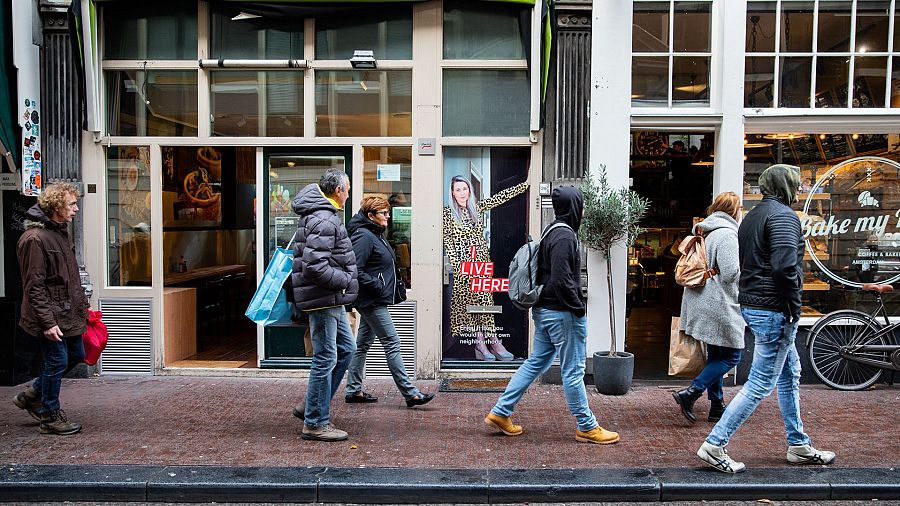 Visitantes del Barrio Rojo pasan frente una de las fotos de la campaña ‘I live here’