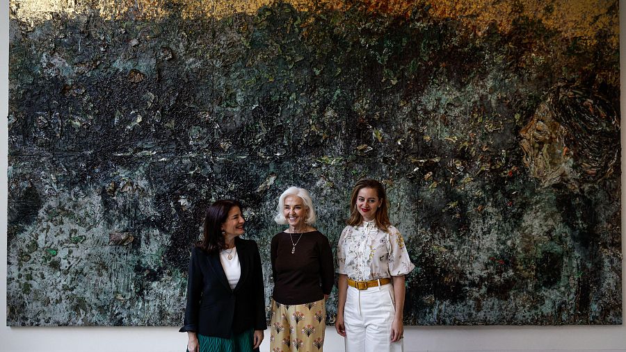 Hortensia Herrero y sus hijas Hortensia y Amparo posan frente a una obra de arte abstracto.