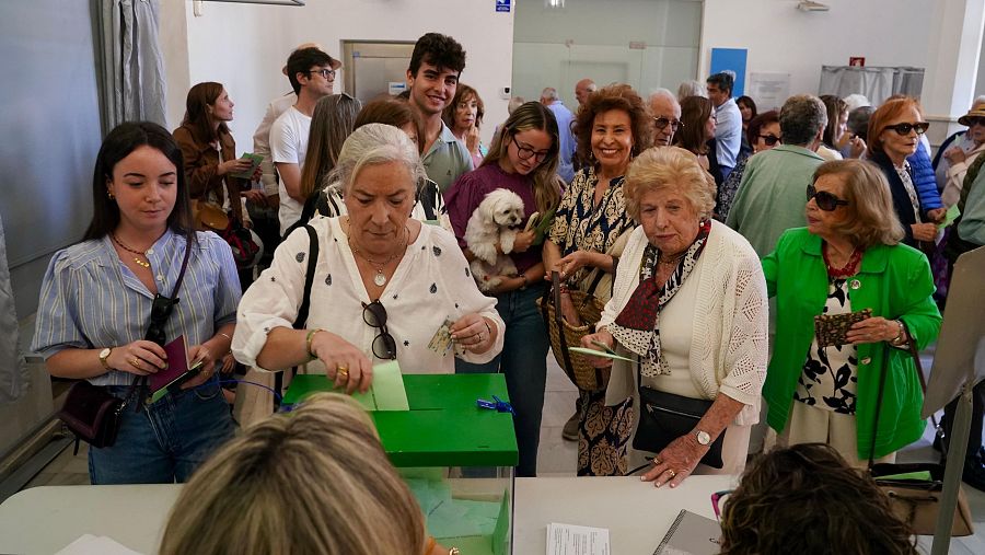 Una mujer deposita su voto mientras un grupo de personas espera su turno detrás