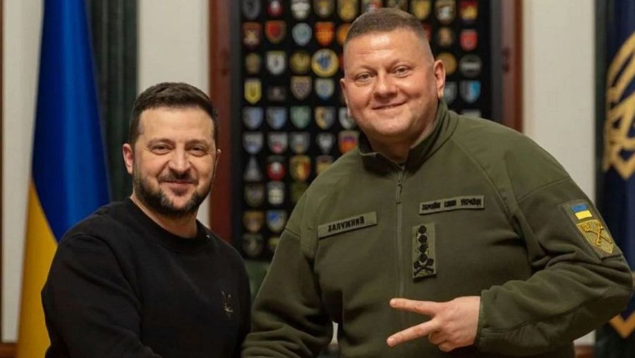 Volodymyr Zelenskyy y el General Valeriy Zaluzhny sonríen posando juntos. Zaluzhny hace un gesto de paz con la mano derecha y lleva una etiqueta con su nombre y galones de cuatro estrellas.