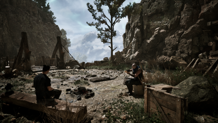 Un asentamiento medieval en plena montaña. Se ve a dos personas sentadas junto a restos de cajas y hogueras apagadas