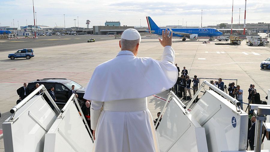 El papa León XIV saluda desde lo alto de la escalerilla del avión a los fotógrafos que le esperan a pie de pista.