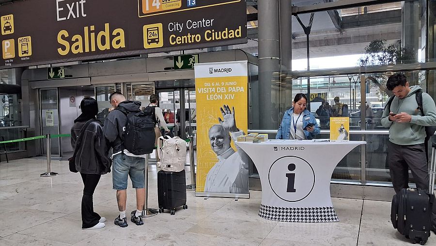 Hay un puesto de información flanqueado por un gran cartel que anuncia la visita del papa a Madrid