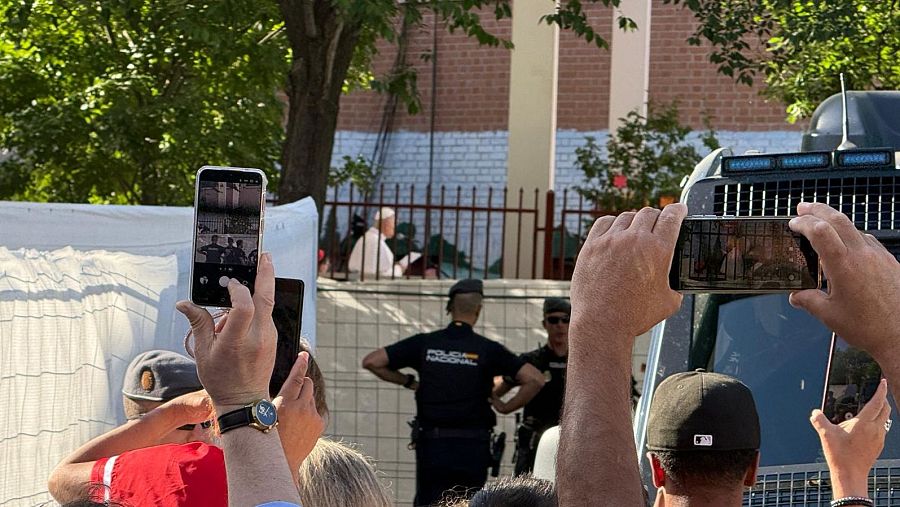Vecinos del barrio de Lucero móvil en ristre, policías asegurando el perímetro y el papa León XIV captado por la cámara de Juanma Cuéllar a su entrada en el patio del Cedia.