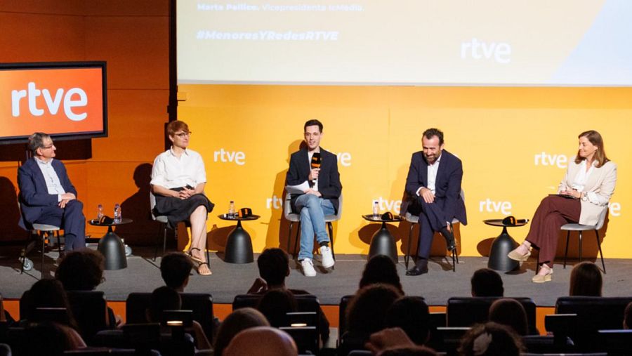 Cinco personas participan en un panel de discusión en un escenario con fondo naranja, destacando el logo de RTVE y el hashtag #MayoresYRedesRTVE.