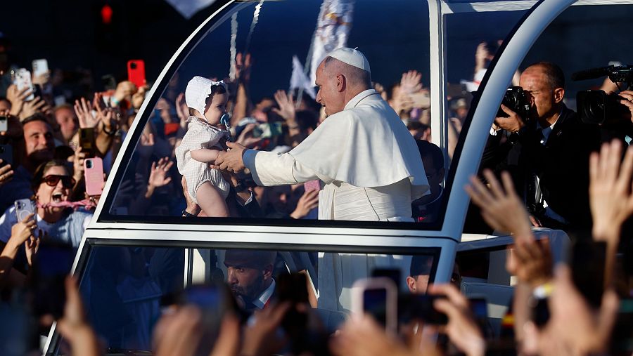 El papa León XIV hace alguna parada para acercarse a varios bebés en su recorrido por Madrid en el papamóvil